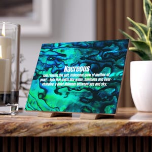 May include: A wooden block with a nacreous design in teal and blue hues. The block is supported by two small wooden stands. The word "Nacreous" is displayed in white text, along with its definition, in a decorative font.