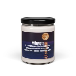 May include: A white candle jar with a black lid. The label features a night scene with a full moon over water and the word "Mångata". The text describes "Mångata" as a Swedish word for the moon's reflection on water.