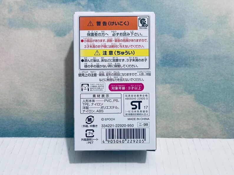 Pu&ograve; includere: Una scatola di prodotto bianca con testo e avvertenze in giapponese. La scatola include un codice a barre, il testo "MADE IN CHINA" e una grafica di un cane. La scatola &egrave; su uno sfondo azzurro e bianco.