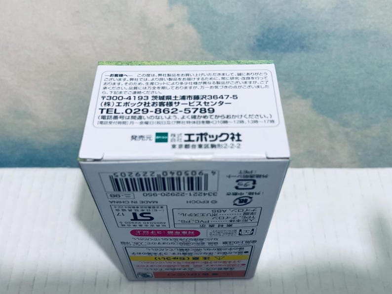 Pu&ograve; includere: Una scatola di prodotto bianca con testo giapponese e una striscia verde nella parte superiore. La scatola ha un codice a barre e la scritta "MADE IN CHINA". La scatola contiene informazioni sul prodotto e dettagli di contatto.