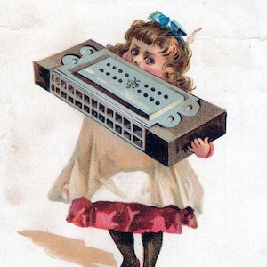 May include: Vintage advertisement featuring a child holding a harmonica. The harmonica is rectangular with a light blue top and dark brown sides. The child is wearing a white dress with a red trim and black stockings. Text at the top reads "Compliments of FRANK MOWREY".