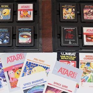 Peut inclure: Une collection de huit cartouches de jeux vidéo Atari 2600 rangées dans un boîtier en plastique noir, accompagnée de sept manuels d'instructions correspondants incluant les titres Pac-Man, Ms. Pac-Man, Asteroids, Space Invaders, Missile Command, Space War, Combat et Vanguard.
