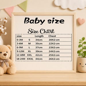 May include: A framed baby size chart with black text. The chart includes sizes from 0-3 months to 18-24 months, with corresponding measurements in centimeters for length and chest. A teddy bear and decorative elements surround the frame.