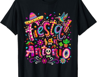 May include: Black t-shirt with a colorful graphic design. The design includes the word "Fiesta" and "San Antonio" in vibrant colors, along with a sombrero, hummingbird, and other festive elements.