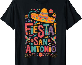 May include: Black t-shirt with a colorful graphic design. The design features the word "Fiesta!" above "San Antonio" with a sombrero, hummingbirds, and floral elements. The text and images are in vibrant colors.