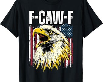 May include: Black t-shirt featuring a graphic of an American bald eagle with an open beak, set against a distressed American flag design. The text "F-CAW-F" is printed above the eagle. The eagle has yellow and white feathers.