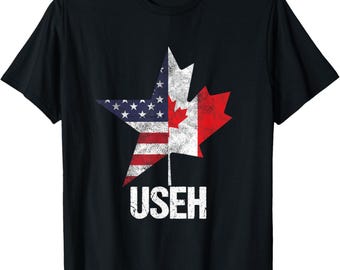 May include: Black t-shirt featuring a star-shaped design that combines the American and Canadian flags. The left side displays the US flag, while the right side shows the Canadian flag. The word "USEH" is printed in white below the design.