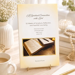 May include: A rectangular book titled A Spiritual Connection with God, 52 Weeks of Scripture, Reflection, and Heartfelt Journaling, featuring the text Draw near to God and He will draw near to you James 4:8 and By Lexis of Love with a central photo.