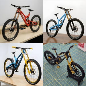 Pode incluir: Quatro bicicletas de montanha em cores diferentes: vermelho, azul e azul escuro, com detalhes amarelos. Cada bicicleta tem pneus grandes e garfos de suspensão, projetados para ciclismo off-road. As bicicletas são exibidas em um fundo neutro.