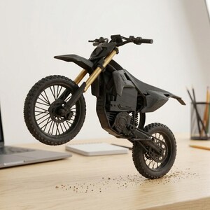 Puede incluir: Una maqueta de motocicleta negra y dorada con la rueda delantera levantada, mostrando sus neum&aacute;ticos y suspensi&oacute;n. La motocicleta est&aacute; sobre un escritorio con un port&aacute;til y un bloc de notas en el fondo. El modelo es detallado y parece impreso en 3D.
