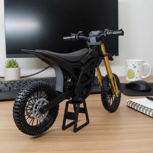 K&ouml;nnte beinhalten: Ein schwarzes und goldenes Miniaturmotorradmodell mit detailliertem Design. Das Modell hat einen schwarzen Rahmen, Sitz und Reifen mit goldfarbenen Vorderradgabeln. Es wird auf einem schwarzen St&auml;nder ausgestellt, der die komplizierten Details des Motorrads zeigt.