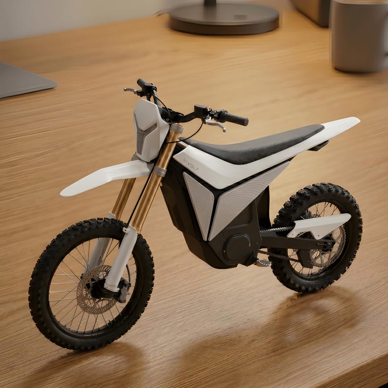 Op de afbeelding: Een witte en zwarte elektrische crossmotor met gouden veervorken. De motor heeft een zwart zadel, zwarte banden en een voorspatbord. De merknaam "VOLT" is zichtbaar aan de zijkant.