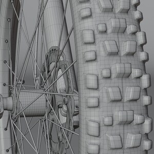 May include: Close-up of a mountain bike wheel and tire. The tire has a deep tread pattern with square knobs for grip. The wheel features a disc brake and a network of spokes. The image is a wireframe rendering.