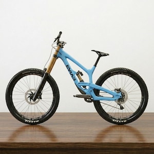 May include: A light blue mountain bike with black tires and gold suspension forks. The bike has the word "EVIAS" printed on the frame. The tires have the word "MAXXIS" printed on them. The bike is on a wooden surface.