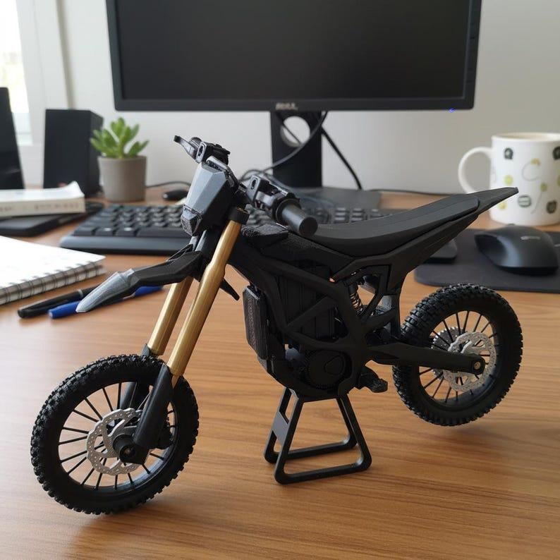 K&ouml;nnte beinhalten: Ein schwarzes und goldenes Miniaturmotorradmodell. Das Modell hat einen schwarzen Sitz, Reifen und Rahmen mit goldenen Vorderradgabeln. Es wird auf einem schwarzen St&auml;nder ausgestellt. Das Motorrad hat ein detailliertes Design.
