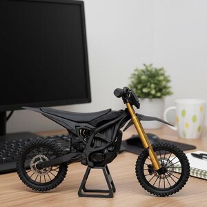 Puede incluir: Modelo en miniatura de motocicleta negra y dorada. El modelo presenta un cuadro, ruedas y asiento negros, con horquillas delanteras doradas. Se exhibe sobre un soporte negro, destacando el dise&ntilde;o de la motocicleta.