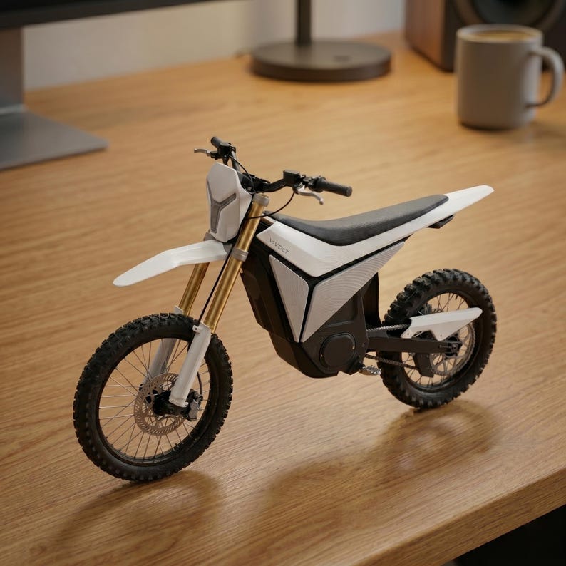 Op de afbeelding: Een witte en zwarte elektrische crossmotor met gouden voorvorken. De motor heeft een zwart zadel, noppenbanden en een koplamp. Het woord "WOLF" is zichtbaar. De motor staat op een houten oppervlak.