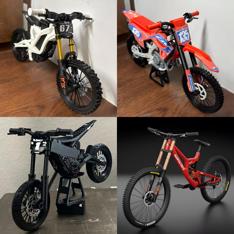May include: Four miniature motorcycles are displayed. A white and black electric dirt bike with gold suspension and the number 67. A red and blue dirt bike with the number 135. A black motorcycle with a stand. A red mountain bike with gold suspension.