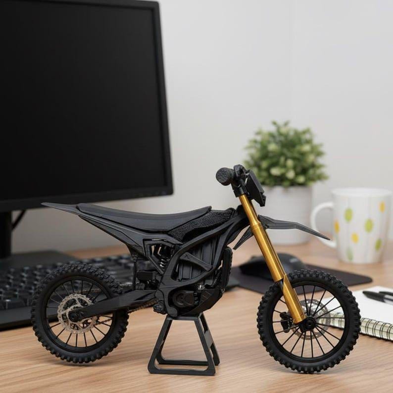 K&ouml;nnte beinhalten: Schwarzes und goldenes Motorradmodell mit detailliertem Design. Schwarzer Sitz, R&auml;der und Rahmen, goldene Vorderradgabeln. Pr&auml;sentiert auf einem schwarzen St&auml;nder, der die feinen Details hervorhebt. Ca. 20 cm lang.