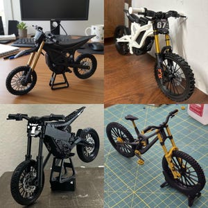 Könnte beinhalten: Vier Miniatur-Motorradmodelle in Schwarz, Weiß und Gold, jeweils mit komplizierten Details. Die Modelle umfassen Dirtbikes und ein Mountainbike, die Federung, Reifen und Rahmendesigns zeigen. Ein Modell hat die Nummer 67 auf der Vorderseite.