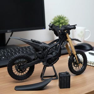 Puede incluir: Una maqueta de motocicleta negra y beige con un dise&ntilde;o detallado. El modelo incluye un asiento, ruedas y un soporte. La motocicleta se exhibe sobre una superficie de madera.