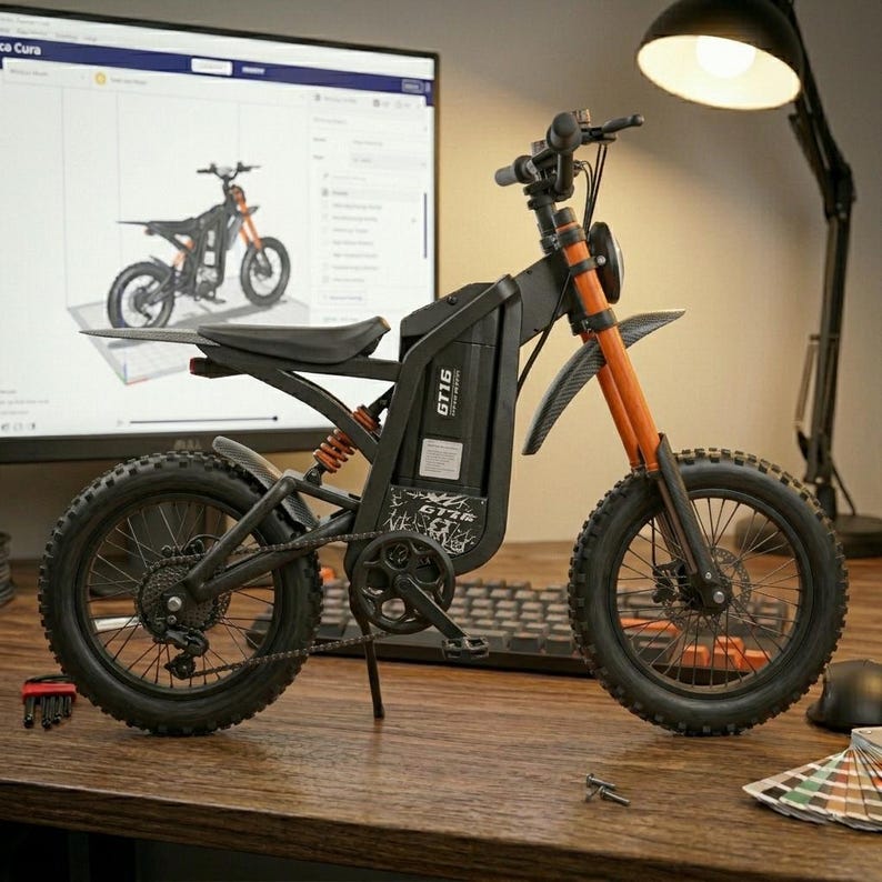 K&ouml;nnte beinhalten: Schwarz-oranges Elektro-Dirtbike mit dem Text "GT16" an der Seite. Das Bike hat einen schwarzen Sitz, Reifen und Rahmen, mit orangefarbener Federung und Gabel. Das Bike steht auf einem Holzschreibtisch.