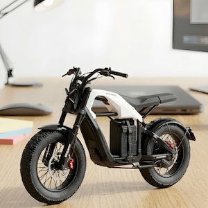 Op de afbeelding: Een zwart-witte elektrische motorfiets met dikke banden en een zwart zadel. Op de motorfiets staat het woord "SEGWAY" gedrukt. De motorfiets staat op een houten bureau.