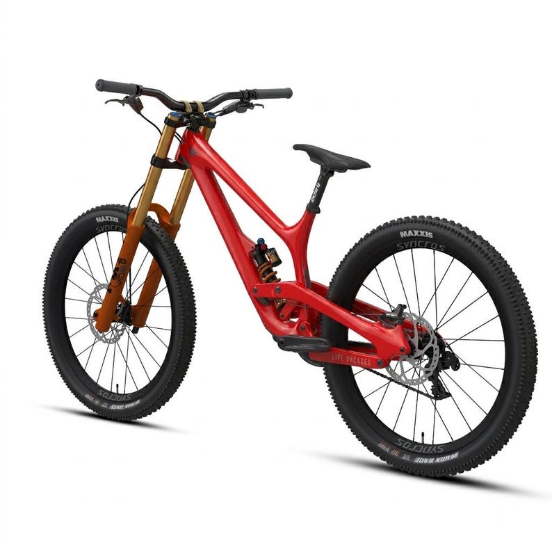 May include: A red mountain bike with black tires and a black seat. The bike has gold-colored front suspension forks and a black handlebar. The tires have the brand name "Maxxis" printed on them.