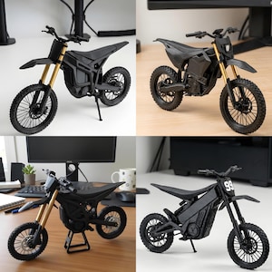 May include: A black electric dirt bike model featuring gold-coloured front suspension forks, knobby tyres with black spokes, a textured frame, and a seat. One version displays the number 99 on the front plate, while others show a plain black front.