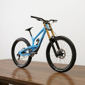 May include: A light blue mountain bike with black tires and gold suspension forks. The bike has a black handlebar and seat. The word "EVIL" is visible on the frame. The bike is on a wooden surface.