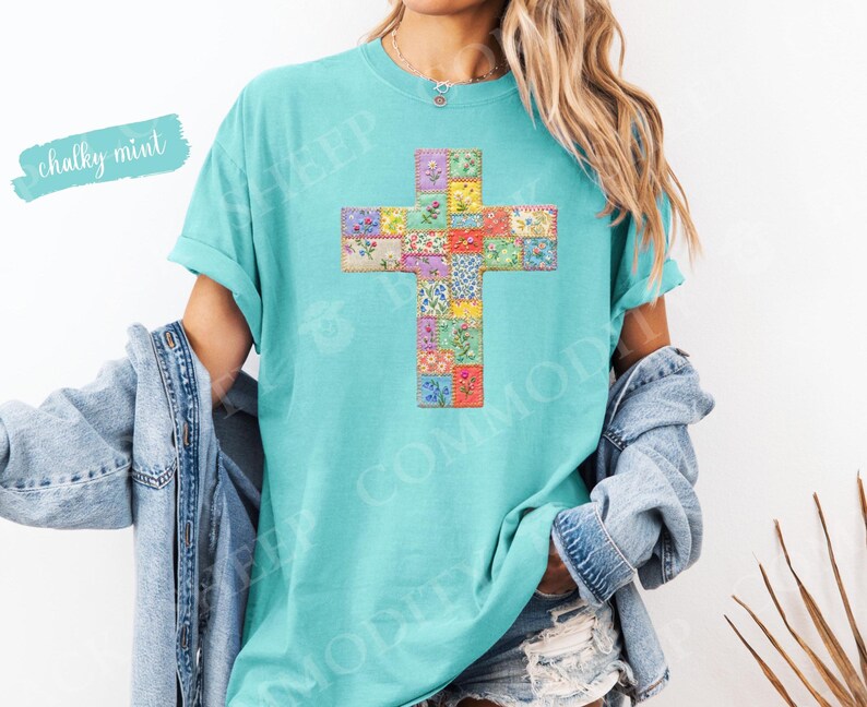 Puede incluir: Una camiseta turquesa con un dise&ntilde;o de cruz hecho de cuadrados de patchwork floral. Las palabras "chalky mint" est&aacute;n escritas en una fuente azul claro en la parte superior izquierda. La camiseta tiene mangas cortas y un corte holgado.