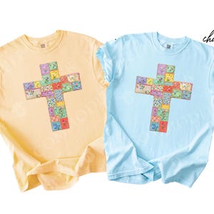 Puede incluir: Dos camisetas de manga corta, una amarilla mantequilla y otra azul claro, cada una con un dise&ntilde;o de cruz. La cruz est&aacute; compuesta por cuadrados de patchwork coloridos con motivos florales. La palabra "butter" est&aacute; escrita en cursiva en la camiseta amarilla, y "chambray" en la azul.