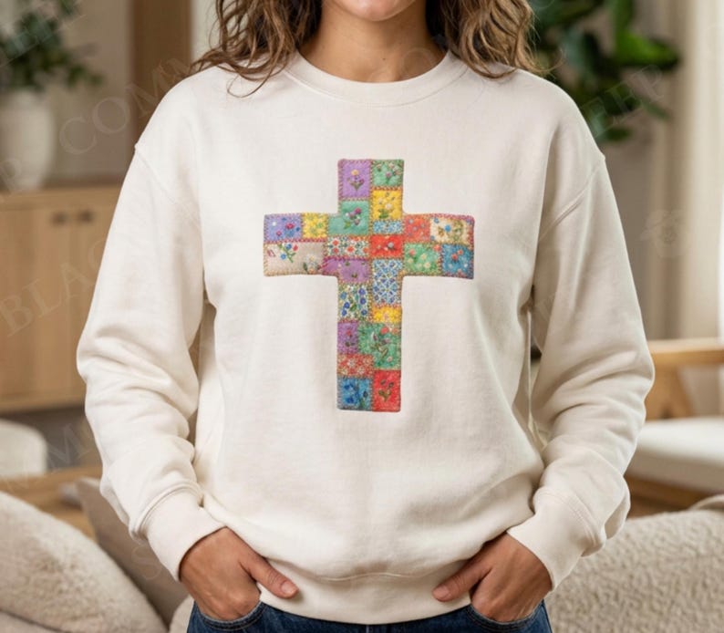 Puede incluir: Sudadera color crema con un dise&ntilde;o de cruz de patchwork colorido. La cruz est&aacute; compuesta por varios cuadrados de tela en tonos rojos, azules, morados y amarillos. La sudadera tiene cuello redondo y mangas largas.