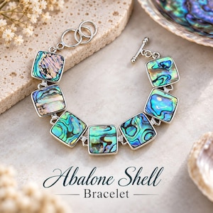 May include: A silver-toned bracelet featuring seven square links inlaid with iridescent abalone shell, displaying vibrant shades of blue, green, and purple. The bracelet includes a toggle clasp and circular rings, with the text Abalone Shell Bracelet.