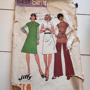 May include: A vintage Simplicity 6451 sewing pattern envelope for Jiffy easy cut easy sew garments. The cover features illustrations of three outfits: a green dress, a white dress, and a brown tunic with wide-leg pants, sized 18 and 20.
