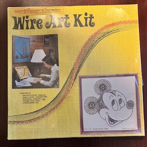 May include: A vintage Walt Disney Character Wire Art Kit featuring Mickey Mouse. The yellow box includes instructions, burlap, nails, wire, hardboard backing, a hanger, and an unassembled frame. The finished art is 12 x 12 inches.