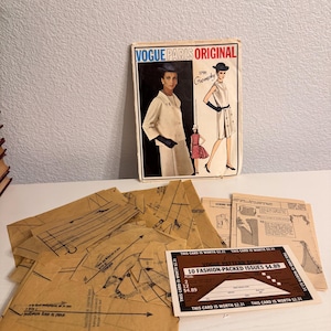 May include: A vintage Vogue Paris Original sewing pattern envelope featuring a Givenchy design, accompanied by multiple brown tissue paper pattern pieces and a small rectangular card labeled Vogue Pattern Book 10 Fashion-Packed Issues $4.89.