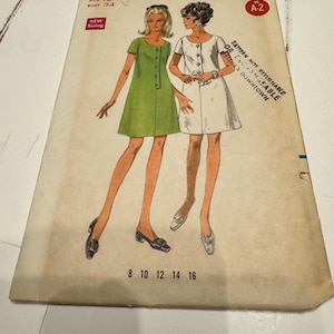 Puede incluir: Una taza de cerámica blanca con un asa negra y el texto "But First, Coffee" en negrita negra. La taza se encuentra sobre un fondo neutro, resaltando su diseño sencillo.