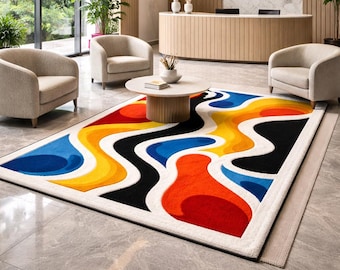May include: A colorful area rug with an abstract design. The rug features a white border and a pattern of flowing shapes in red, orange, yellow, blue, and black. The rug is placed on a gray tiled floor in a modern interior setting.