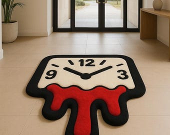 Puede incluir: Una alfombra única con forma de reloj derritiéndose. La alfombra presenta una esfera blanca con números y manecillas negras, un borde negro y un diseño rojo que se derrite. La alfombra está colocada sobre un suelo embaldosado.