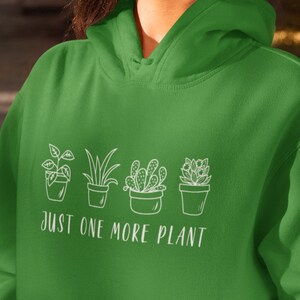 May include: A green hoodie with a white graphic of four potted plants and the text "Just One More Plant".