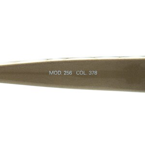 May include: Close-up of a section of a pair of eyeglasses. The frame is a light brown colour. The text "MOD. 256 COL. 378" is printed on the frame.