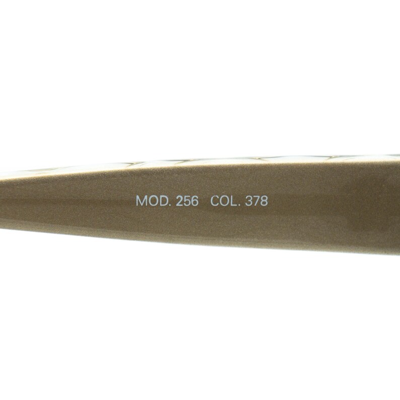 May include: Close-up of a section of a pair of eyeglasses. The frame is a light brown colour. The text "MOD. 256 COL. 378" is printed on the frame.