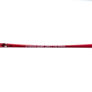 May include: A red eyeglass frame with the text "STADIUM 6258R 53▢17 135 NR666" printed in white. The frame is a vibrant red color and appears to be made of metal.