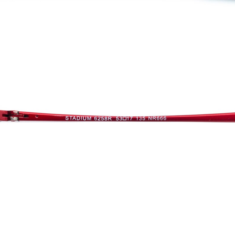 May include: A red eyeglass frame with the text "STADIUM 6258R 53▢17 135 NR666" printed in white. The frame is a vibrant red color and appears to be made of metal.