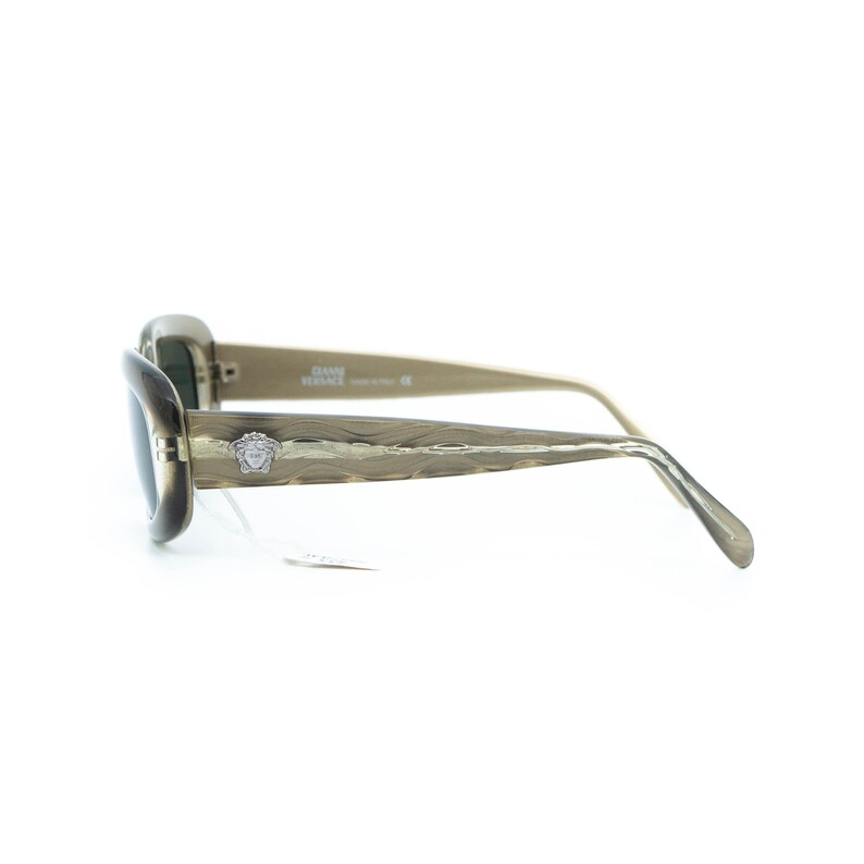 May include: Olive-toned sunglasses with dark lenses. The frames feature a textured pattern and a small silver emblem. The arms are a lighter olive shade. The sunglasses are set against a white background.