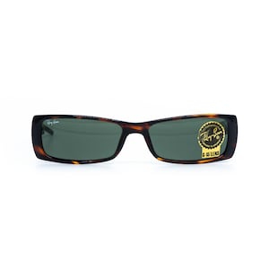 Puede incluir: Gafas de sol rectangulares con montura carey y lentes verdes. El logotipo de Ray-Ban es visible en la lente izquierda, y una etiqueta en la lente derecha dice "UV Protection" y "G-15 Lens".
