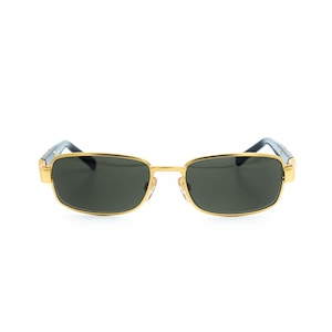 May include: Gold-framed sunglasses with dark lenses. The rectangular frames have a gold finish, with dark blue accents on the temples. The lenses are a dark, solid color, providing a sleek and stylish look.