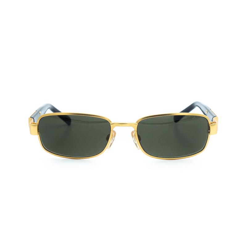 May include: Gold-framed sunglasses with dark lenses. The rectangular frames have a gold finish, with dark blue accents on the temples. The lenses are a dark, solid color, providing a sleek and stylish look.