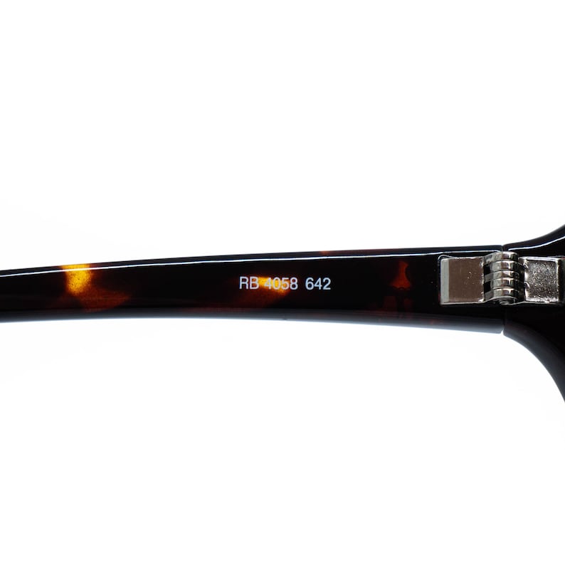 Puede incluir: Primer plano de la patilla de unas gafas. La montura tiene un patr&oacute;n de carey con el texto "RB 4058 642" impreso en blanco. La bisagra es plateada.